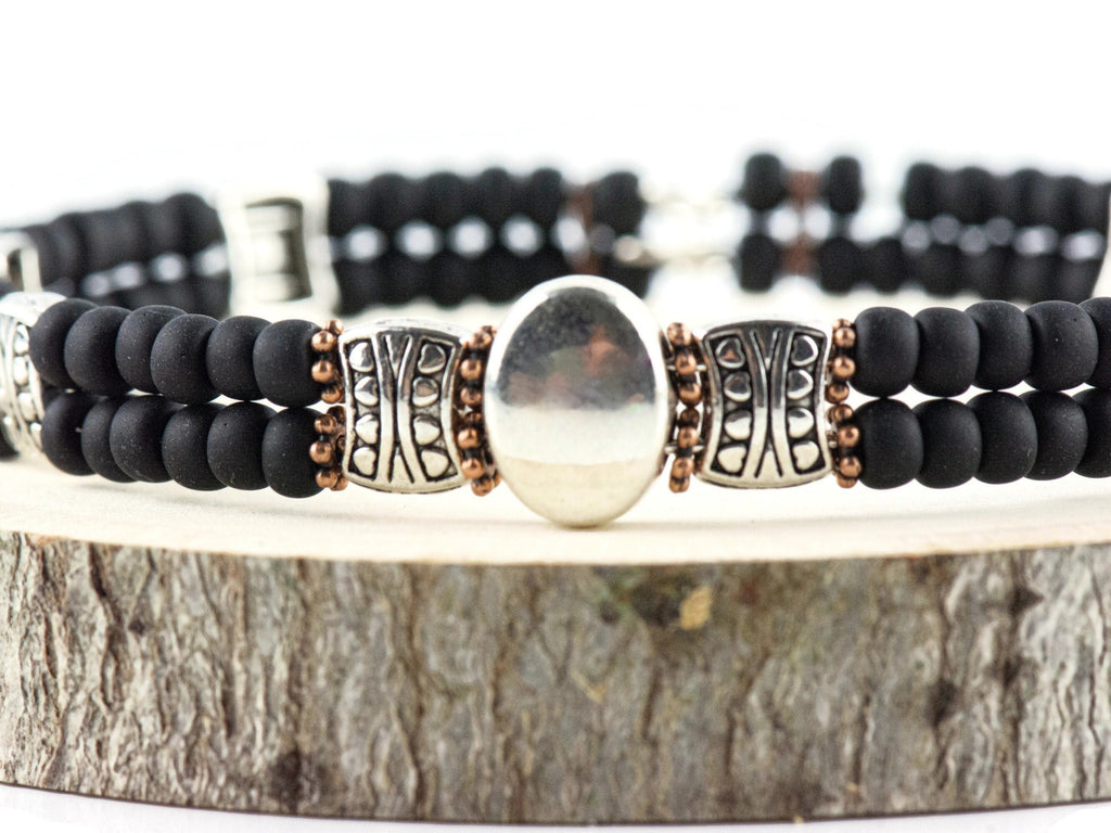 Button and Bows Jet Black Cuff Memory Wire Bracelet close up on a wood piece with tree bark edging