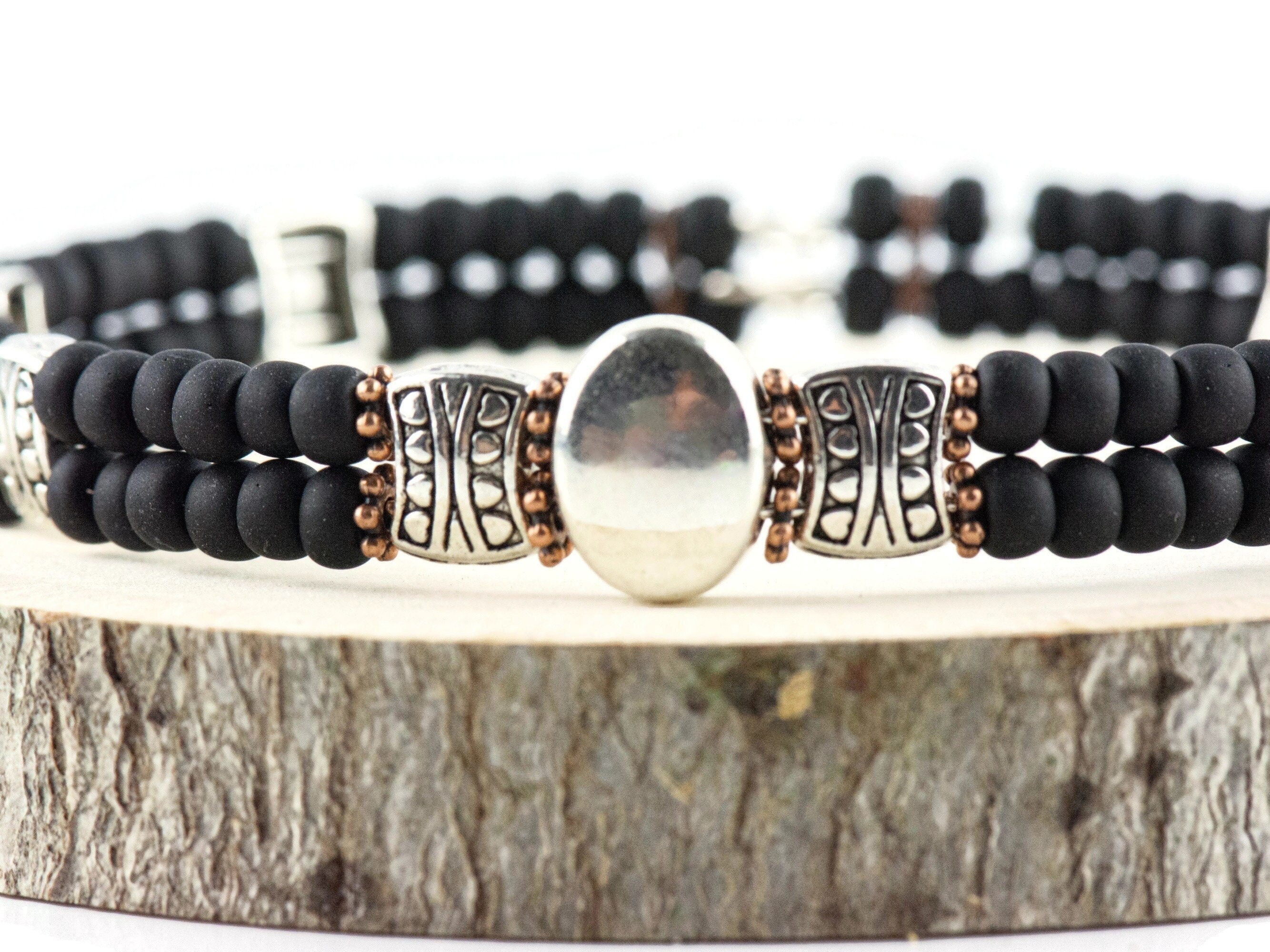 Button and Bows Jet Black Cuff Memory Wire Bracelet close up on a wood piece with tree bark edging