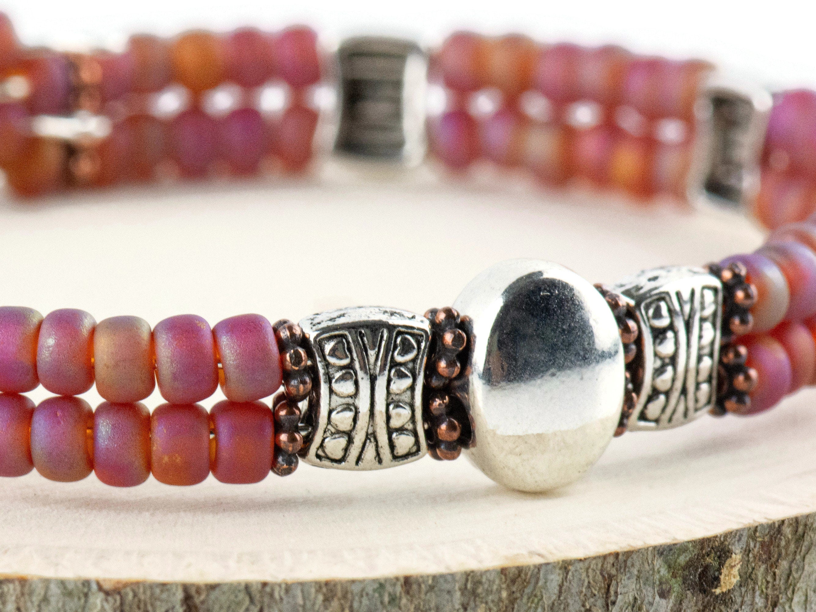 Button and Bows Raspberry Sorbet Cuff Memory Wire Bracelet close up on a wood piece with tree bark edging
