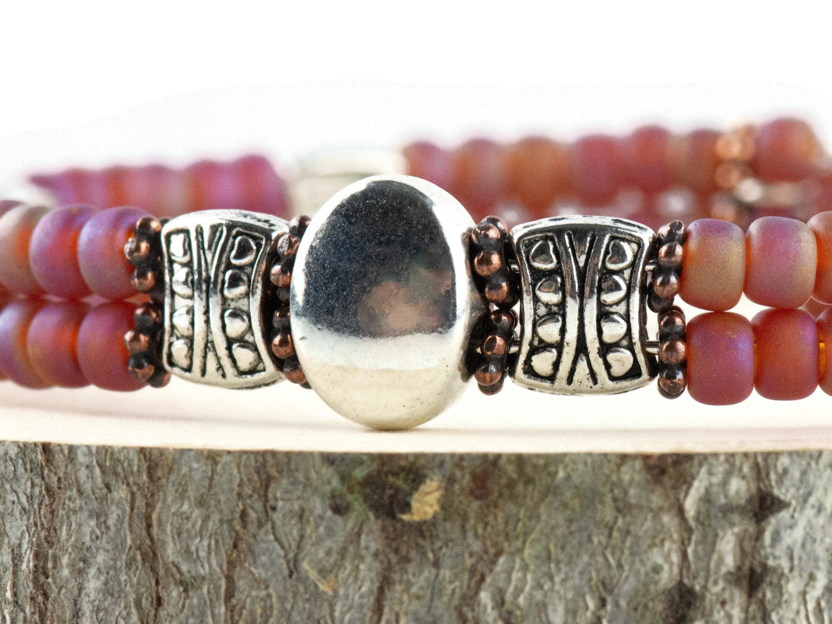 Button and Bows Raspberry Sorbet Cuff Memory Wire Bracelet close up on a wood piece with tree bark edging