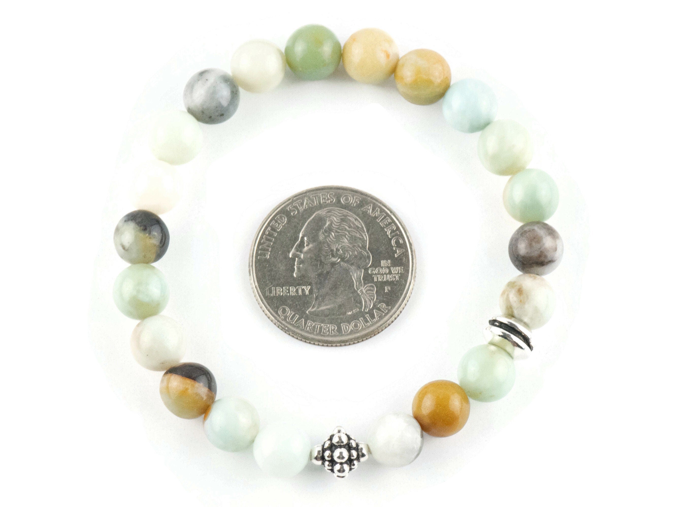 Black Gold Amazonite Genuine Gemstone Stretch Bracelet on white background. Amazonite beads are multicolor earth-tones. Center bead is a silver Bali style bead. Quarter in center of bracelet is for a size reference.