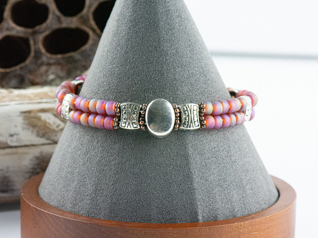 Button and Bows Raspberry Sorbet Cuff Memory Wire Bracelet on a decorative black bracelet stand