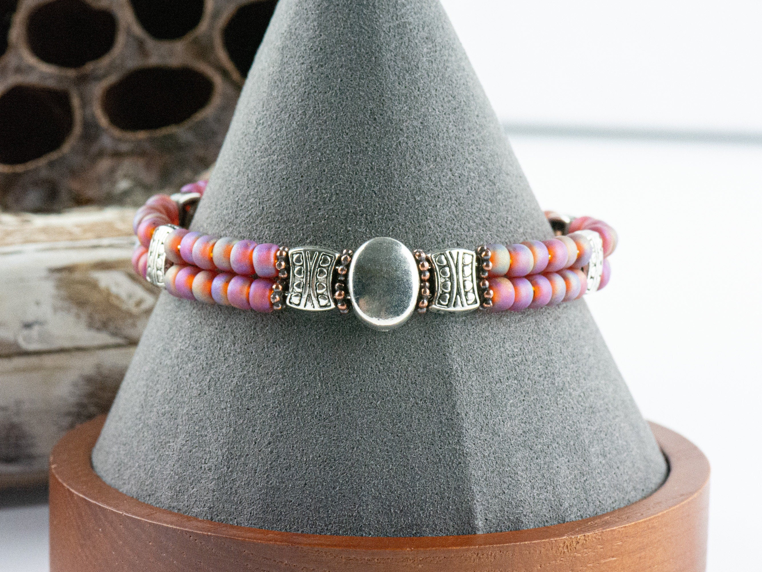 Button and Bows Raspberry Sorbet Cuff Memory Wire Bracelet on a decorative black bracelet stand